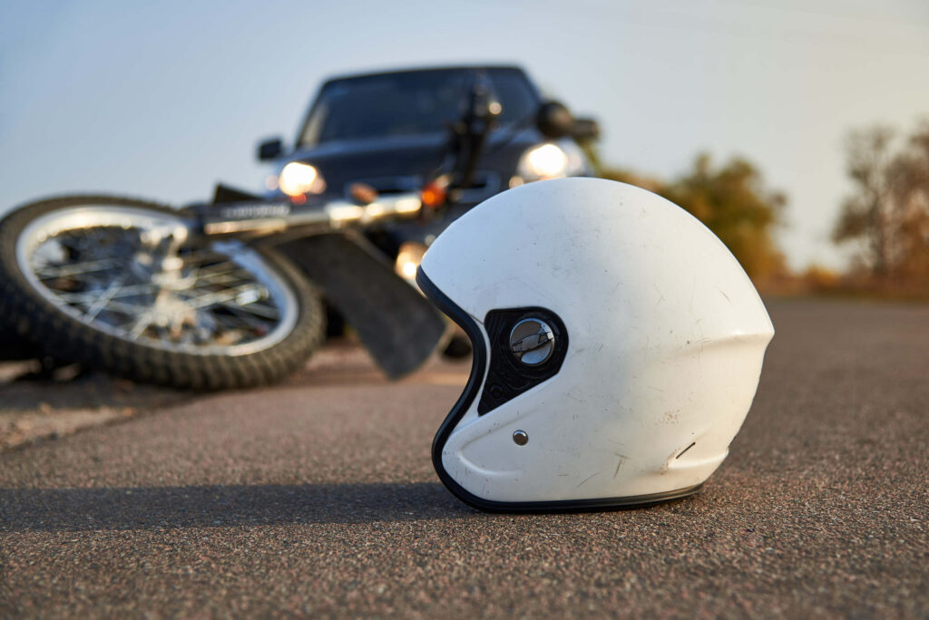 A white motorcycle helmet rests on a Utah County road after a crash, highlighting the importance of safety gear in insurance claims.