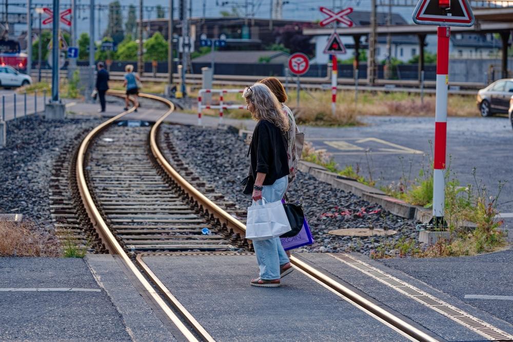Sunset at Lenzburg railway station with senior women crossing railway tracks on a late spring evening.