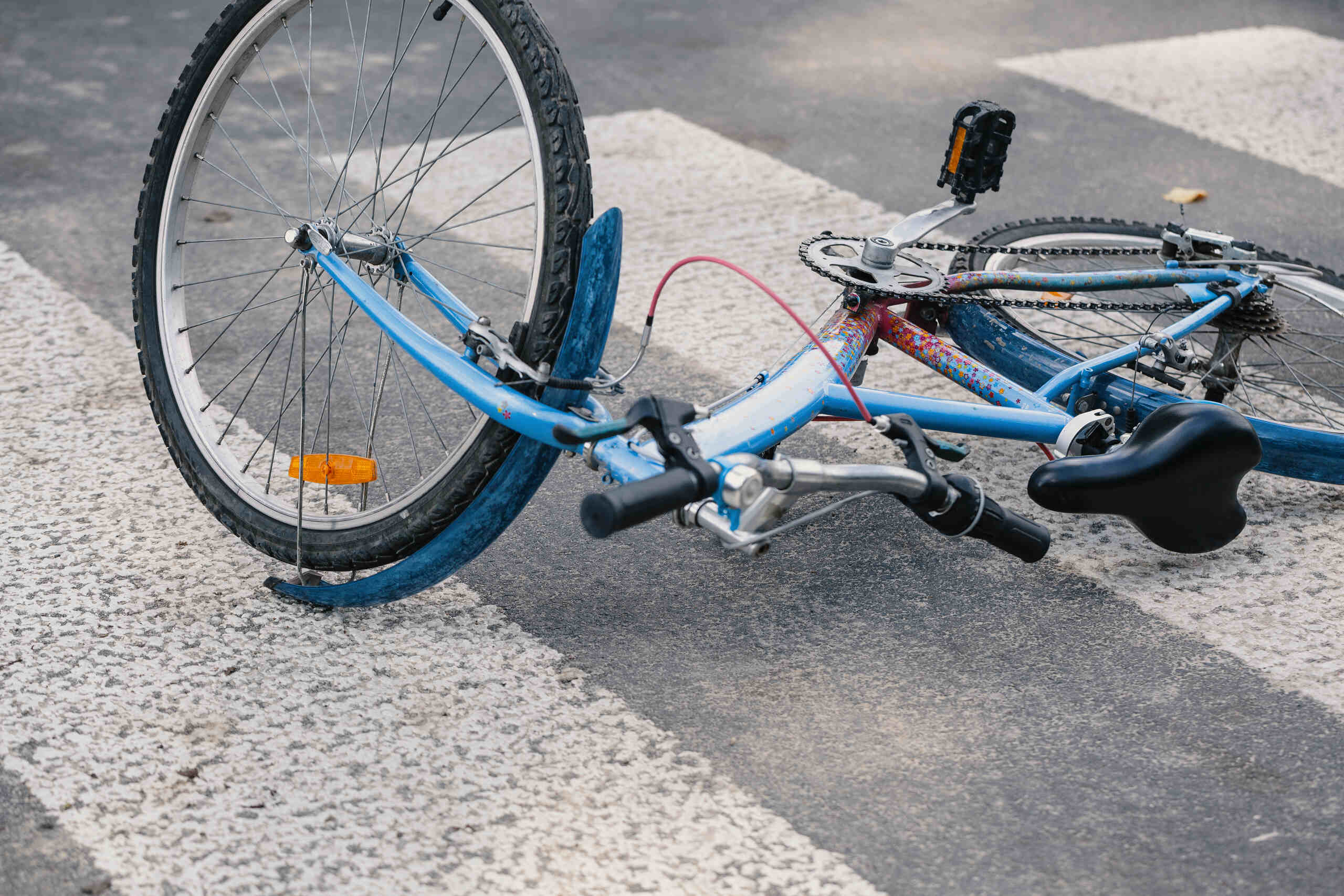 Blue bicycle damaged after hitting a pothole on a Midvale City road.