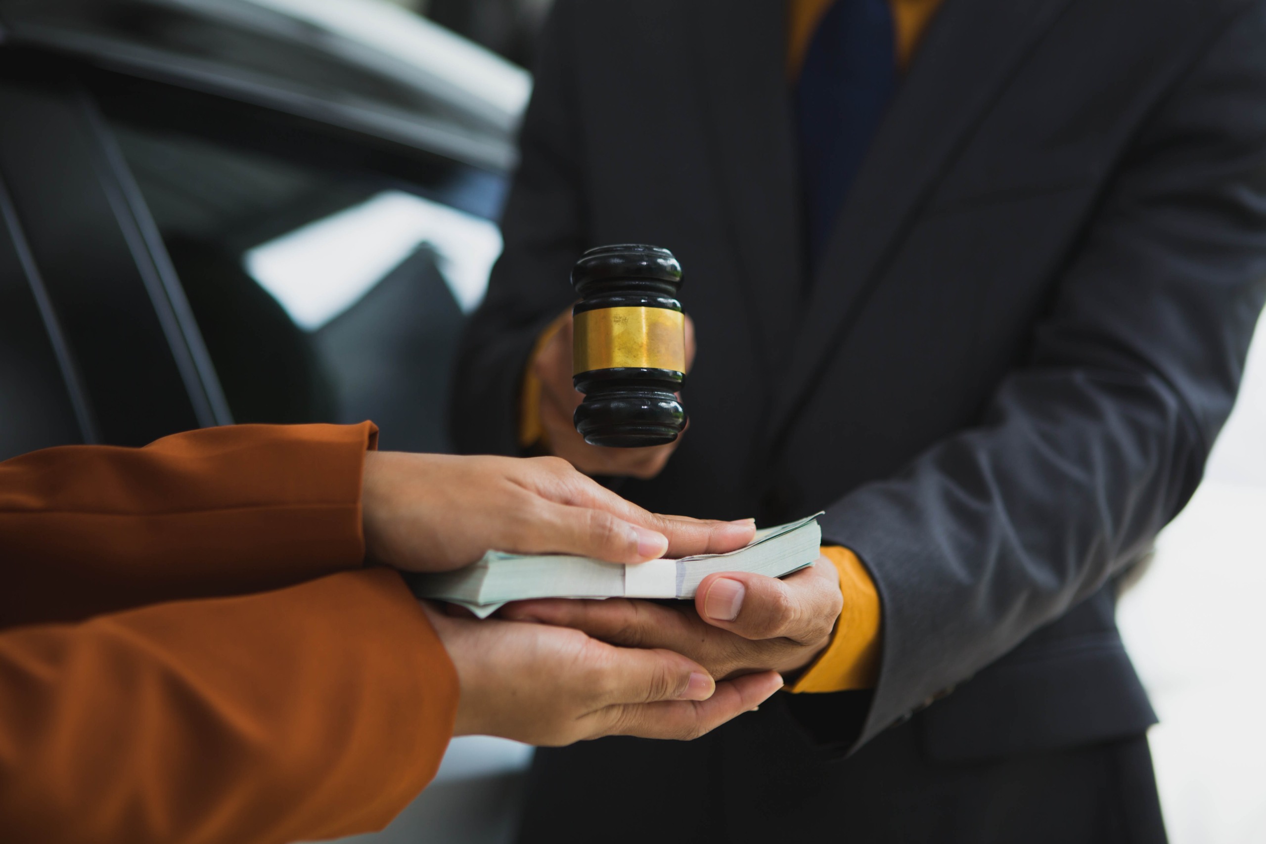 A Salt Lake City car accident victim receives a cash settlement from a legal professional holding a gavel.