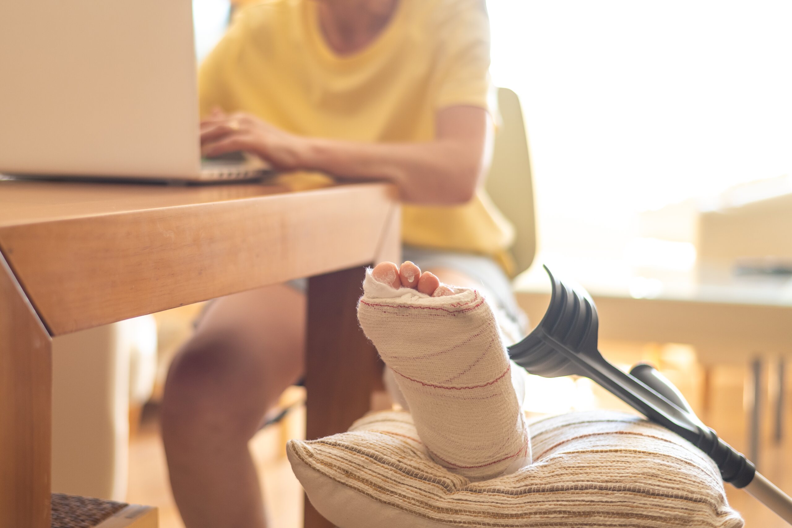 Tenant with a leg cast and crutches working at home, illustrating Midvale apartment complex injuries and potential premises liability claims against a landlord.