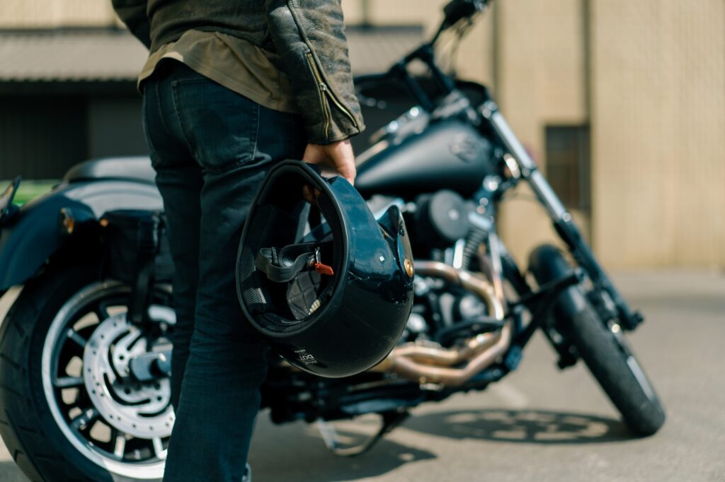 An Idaho Falls rider holding a helmet while standing next to his motorcycle.