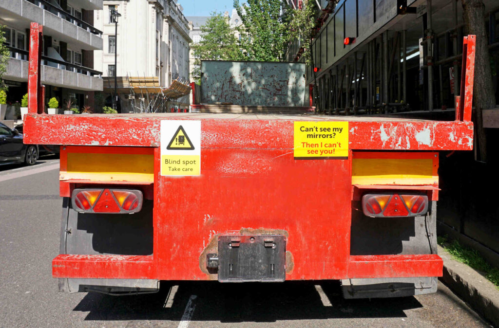 Rear view of a semi-truck on I-80 showing blind spot liability warnings.
