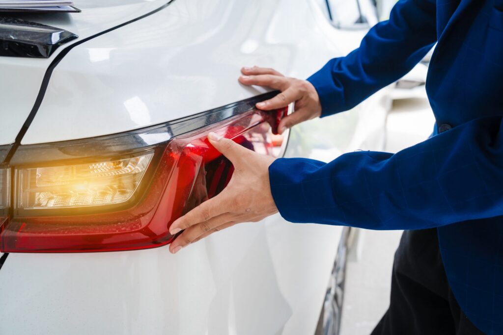 Mechanic examining damaged rear tail light after crash illustrating Utah underinsured motorist claims and injury compensation limits