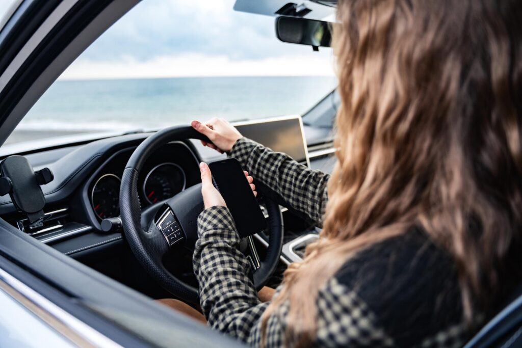 A young driver distracted by a mobile device, illustrating the "negligent entrustment" factors often present in Idaho Falls minor DUI cases.