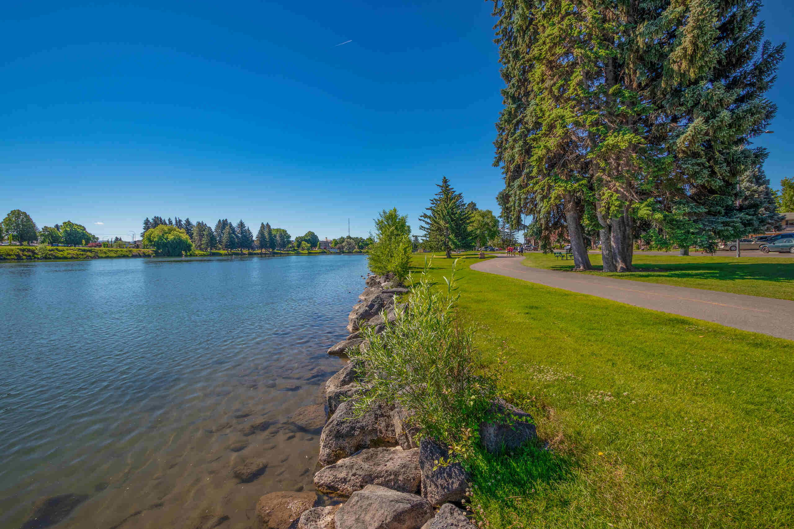 A scenic view of the paved walking and cycling path on the Idaho Falls Greenbelt near the Snake River.