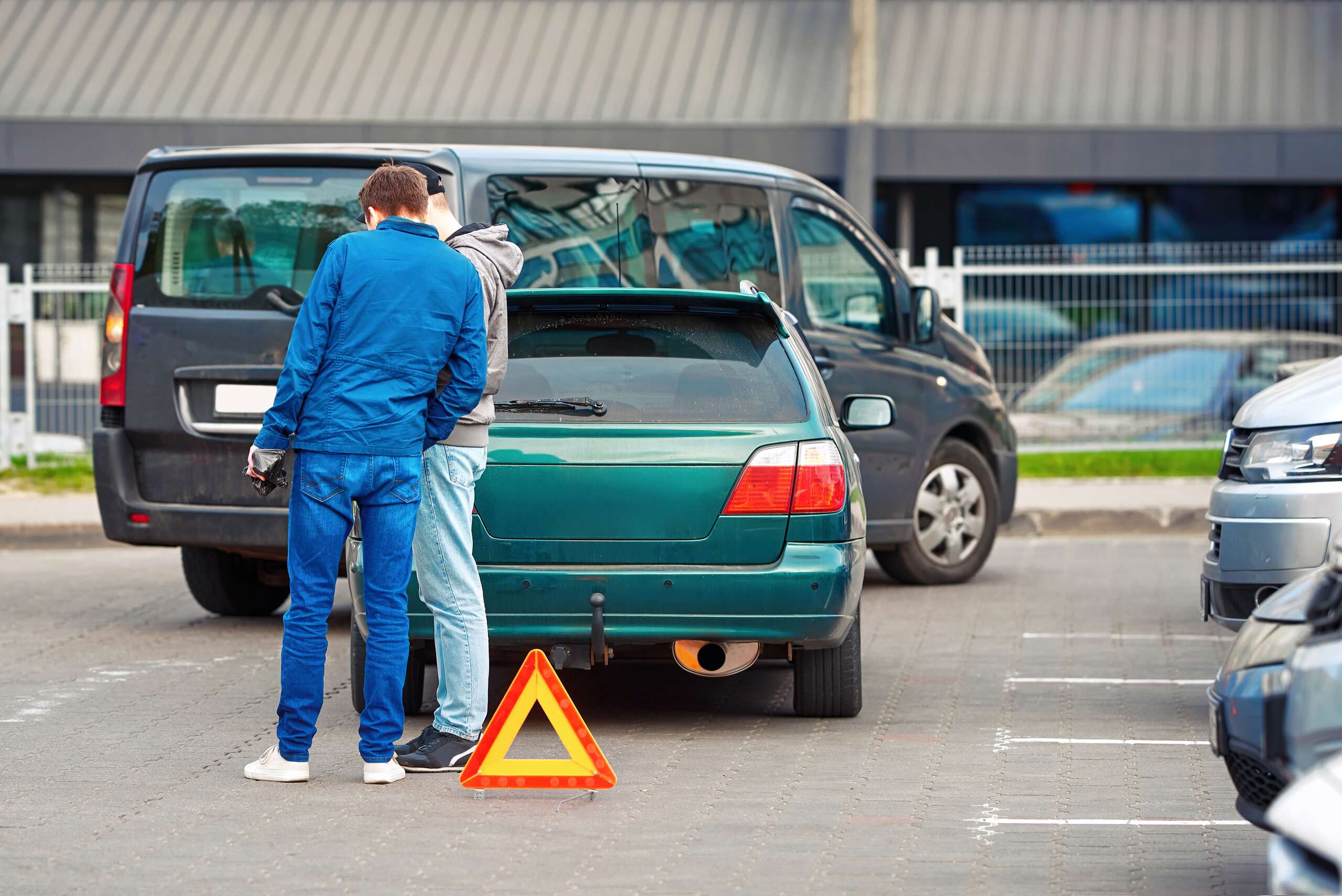 Two drivers discussing fault and property damage after a parking lot collision in a Midvale commercial area.