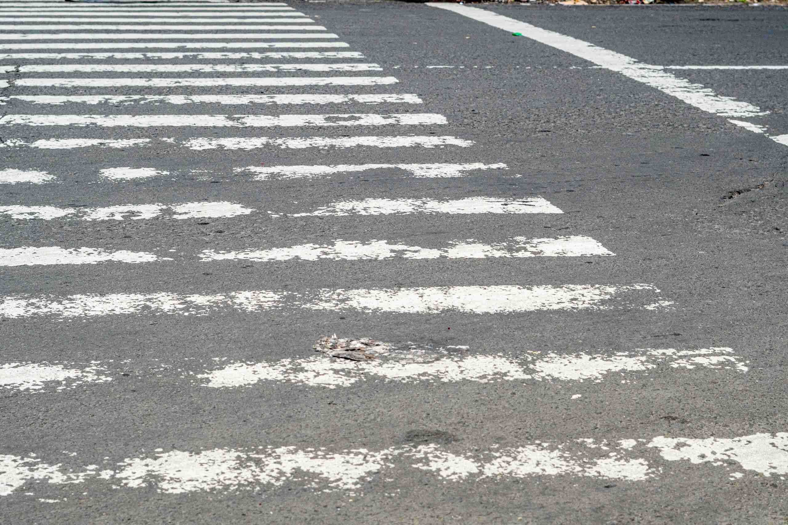 Faded and worn unmarked crosswalk markings on a Midvale roadway, highlighting driver yield requirements under Utah law.