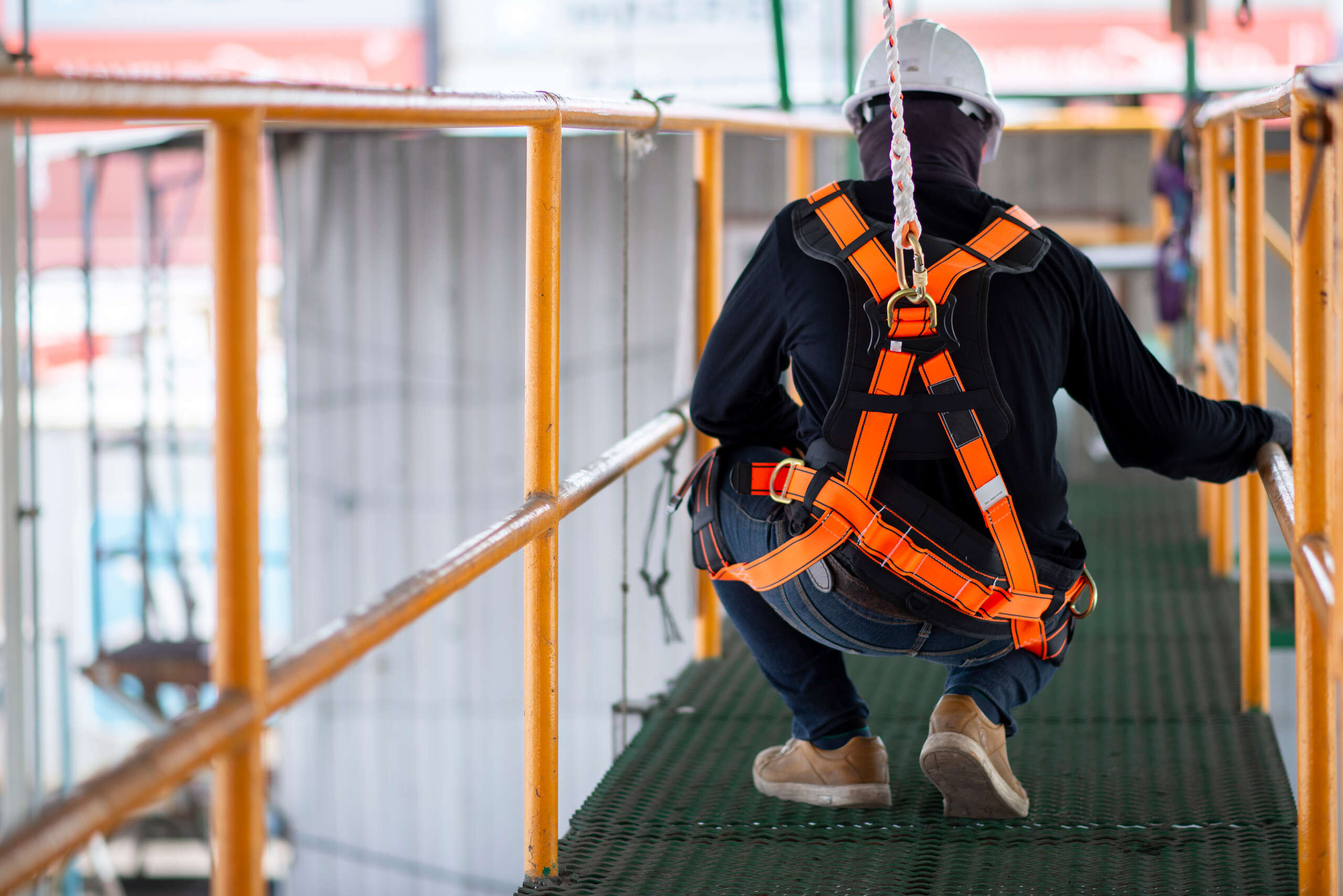 A construction subcontractor wearing a safety harness and helmet on an Ogden job site, illustrating potential third-party liability for falls.