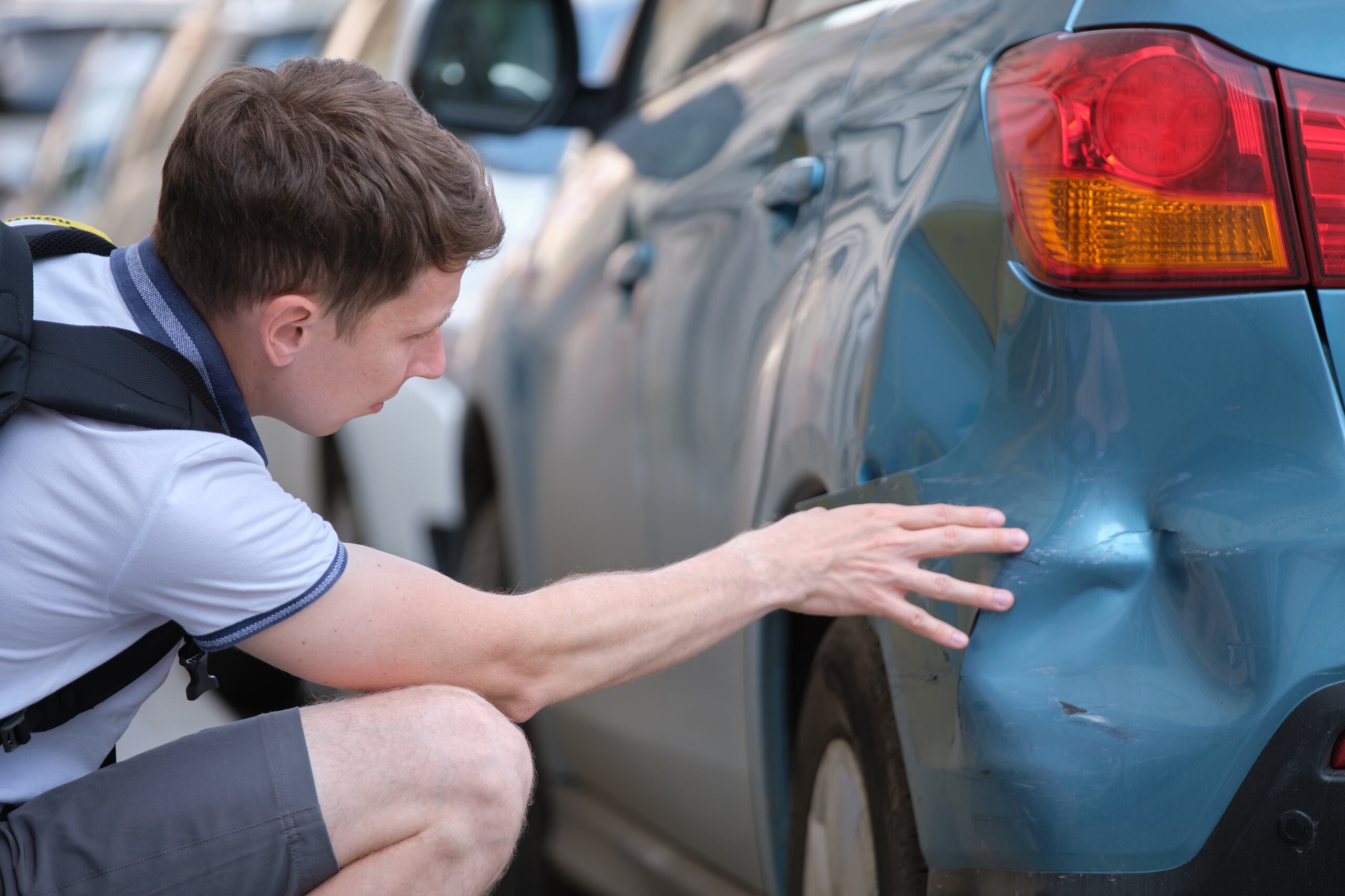 Victim inspecting vehicle damage after an Ogden hit-and-run accident to support an injury claim.