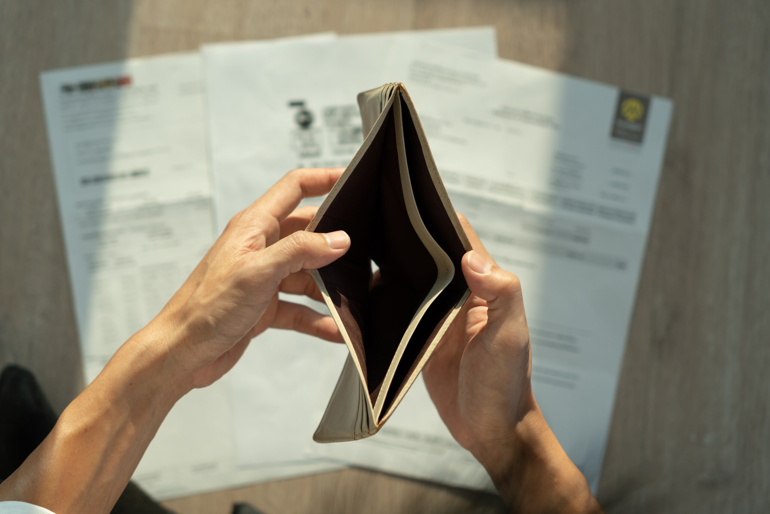 An injured driver holding an empty wallet over unpaid medical bills after a car accident in Ogden.