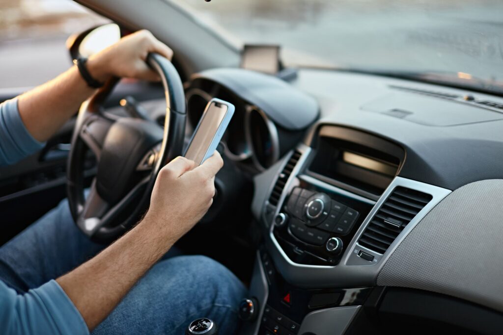 Distracted driver texting behind the wheel in Provo, impacting car accident liability and compensation.