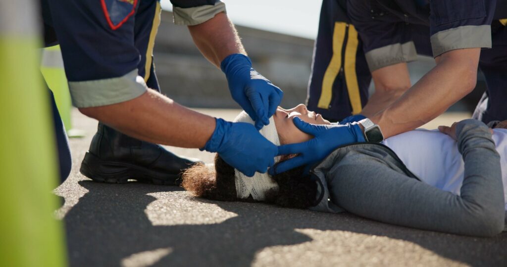 Emergency responders provide immediate medical care to an accident victim with a head injury.