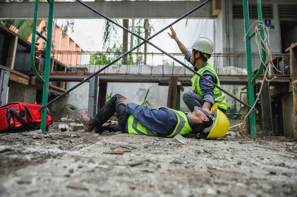 A high-angle view of several construction workers in safety gear walking across a large, complex rebar grid at a building site.