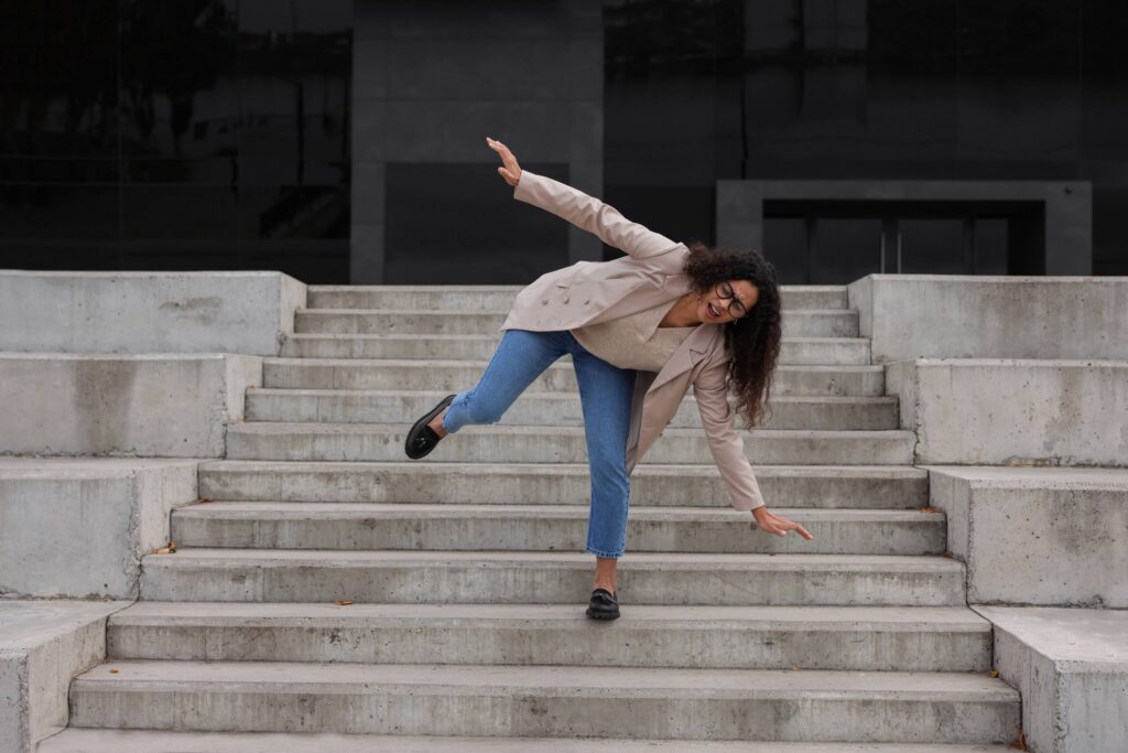 A woman losing her balance on outdoor concrete steps illustrates slip and fall claims handled by Rock Springs Premises Liability Lawyers.