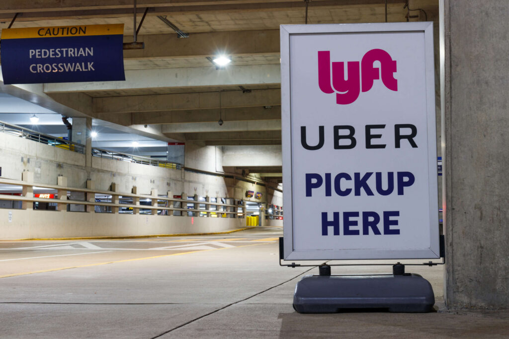 A Lyft and Uber pickup sign in a parking garage illustrates key coverage zones related to Spokane Rideshare Accident Liability.