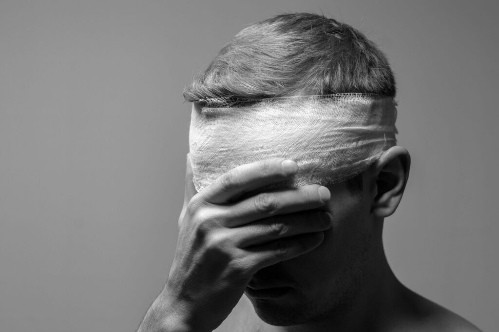 A man with a bandage wrapped around his head covering his eyes illustrates head trauma cases represented by Spokane Brain Injury Lawyers.
