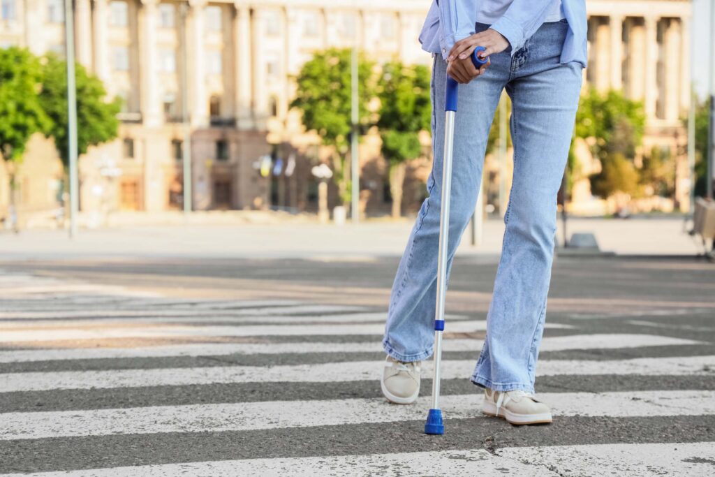 An injured person using a cane to walk across a crosswalk relates to claims represented by Spokane Pedestrian Accident Lawyers.